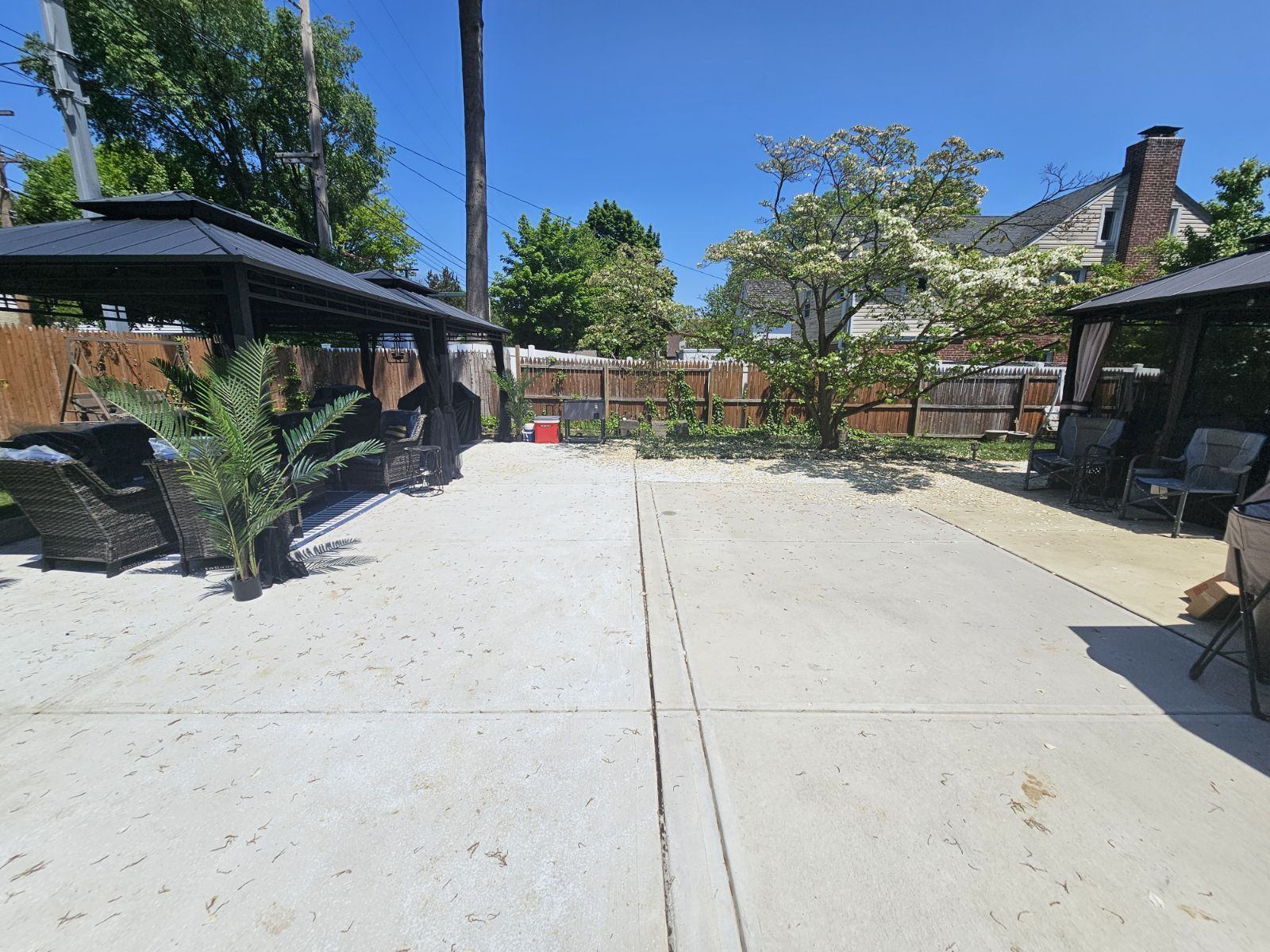 Large backyard concrete patio with gazebos